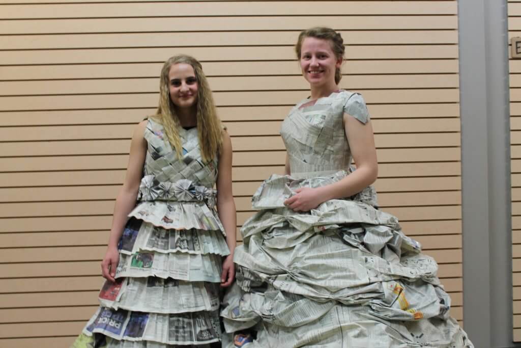 Two girls pose in dresses made of newspaper