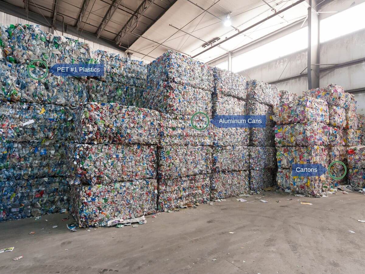 Bales of PET #1 Plastics, aluminium cans, and cartons stacked in large rows at a Material Recovery Facility in Manitoba